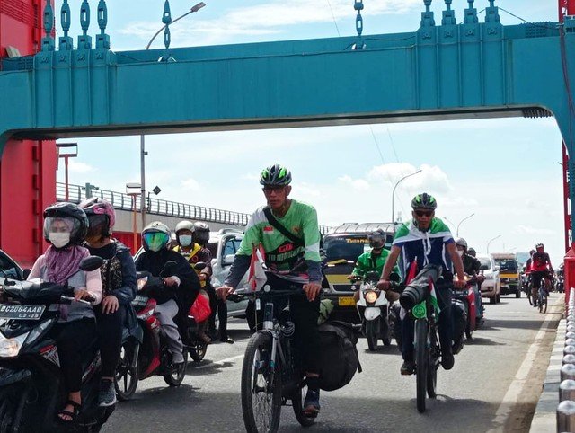 Dua pria asal Tanggerang Selatan, Banten, Tjahaja Gunawan dan Muhammad Fuad sedang menempuh perjalanan menuju tanah suci Makkah dan kini sudah sampai di jembatan Ampera Palembang, Sabtu (18/12/2021).