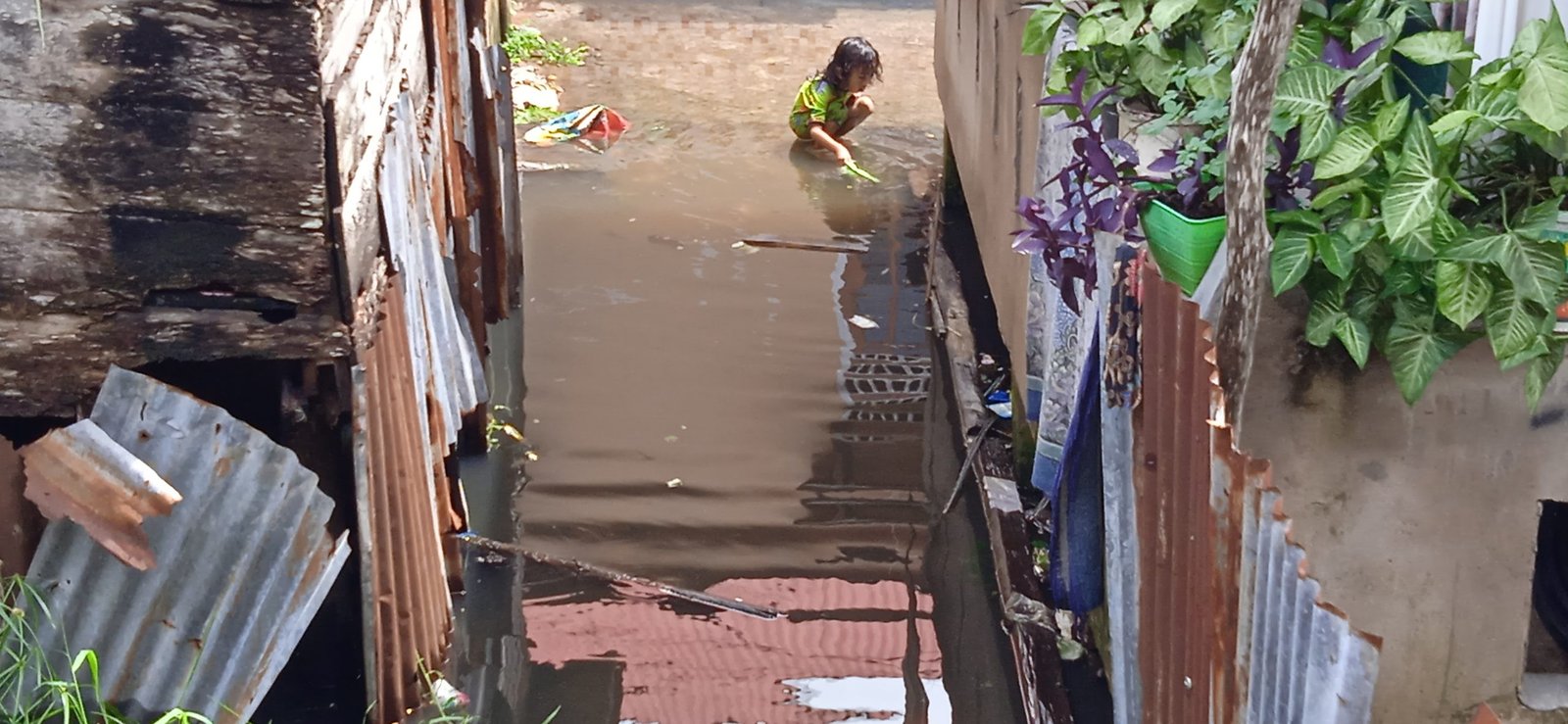 Anak kecil warga Aroni bermain air saat banjir, Sabtu (25/12/2021).