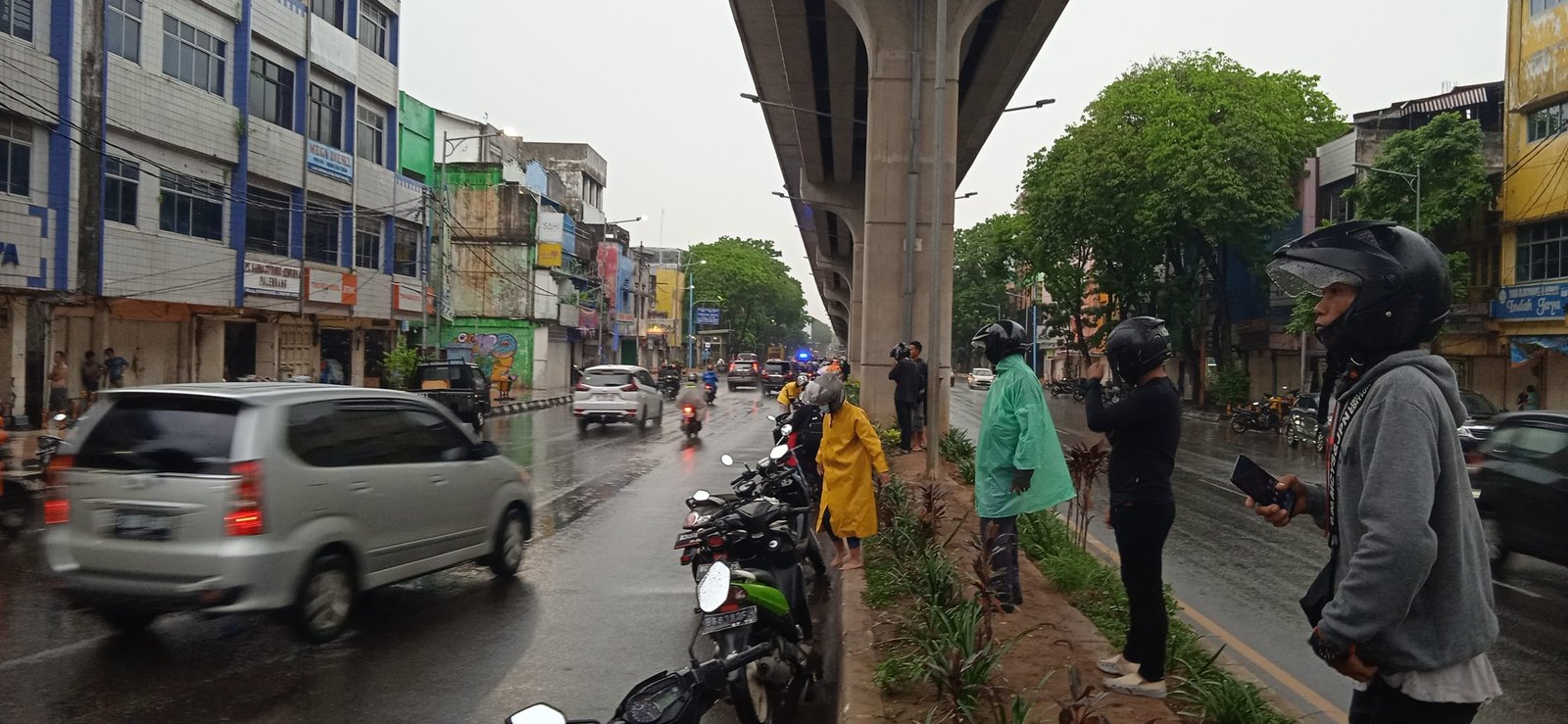Pengendara motor sedang berteduh di bawah jembatan LRT Jalan Jenderal Sudirman, Jumat (7/1/2022).