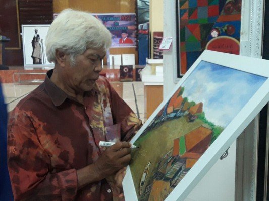Suharno Manap salah seorang pelukis senior Palembang saat menandatangani sebuah lukisan