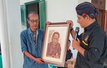 Ariyanto sedang menerima lukisan dirinya yang berasal dari ampas kopi dari Karya Rudi Winarso (Foto: Jogkem Grup)