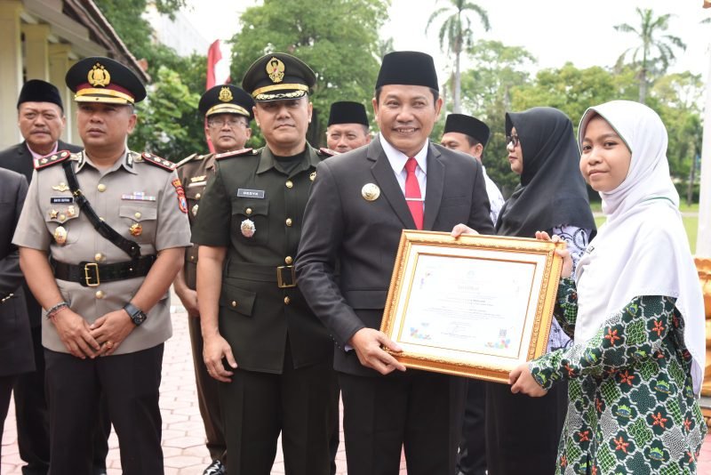Bupati Sidoarjo Subandi menyerahkan berbagai penghargaan kepada guru dan siswa di sela peringatan Hari Pendidikan Nasional, Jumat (2/5/2025). (Foto: Kominfo Sidoarjo)