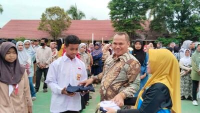 Kepala Sekolah SMP N 12 Palembang, Suparman Sunaryo, S.Pd., M.Pd saat menyerahkan seragam sekolah gratis bantuan dari Walikota Palembang kepada siswa secara simbolis