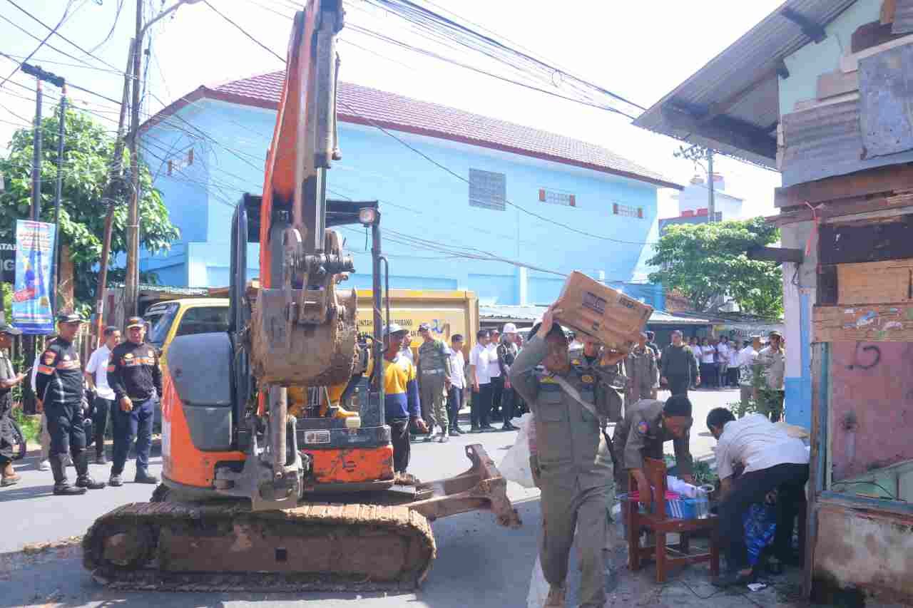 Satuan Polisi Pamong Praja Kota Palembang membongkar rumah dan kios di Jalan Puncak Sekuning, di dekat SMA Negeri 2, Rabu (26/11/2025)